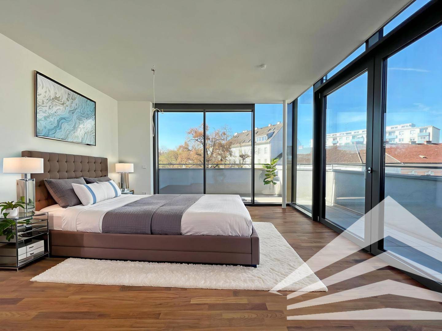 Modernes Schlafzimmer mit Holzboden, großem Bett und Zugang zu einer sonnigen Terrasse.