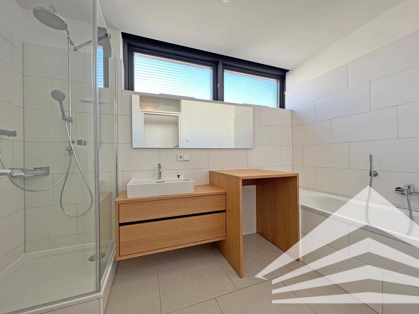 Modernes Badezimmer mit Dusche, Badewanne, Holzwaschtisch und Fenster für Tageslicht.