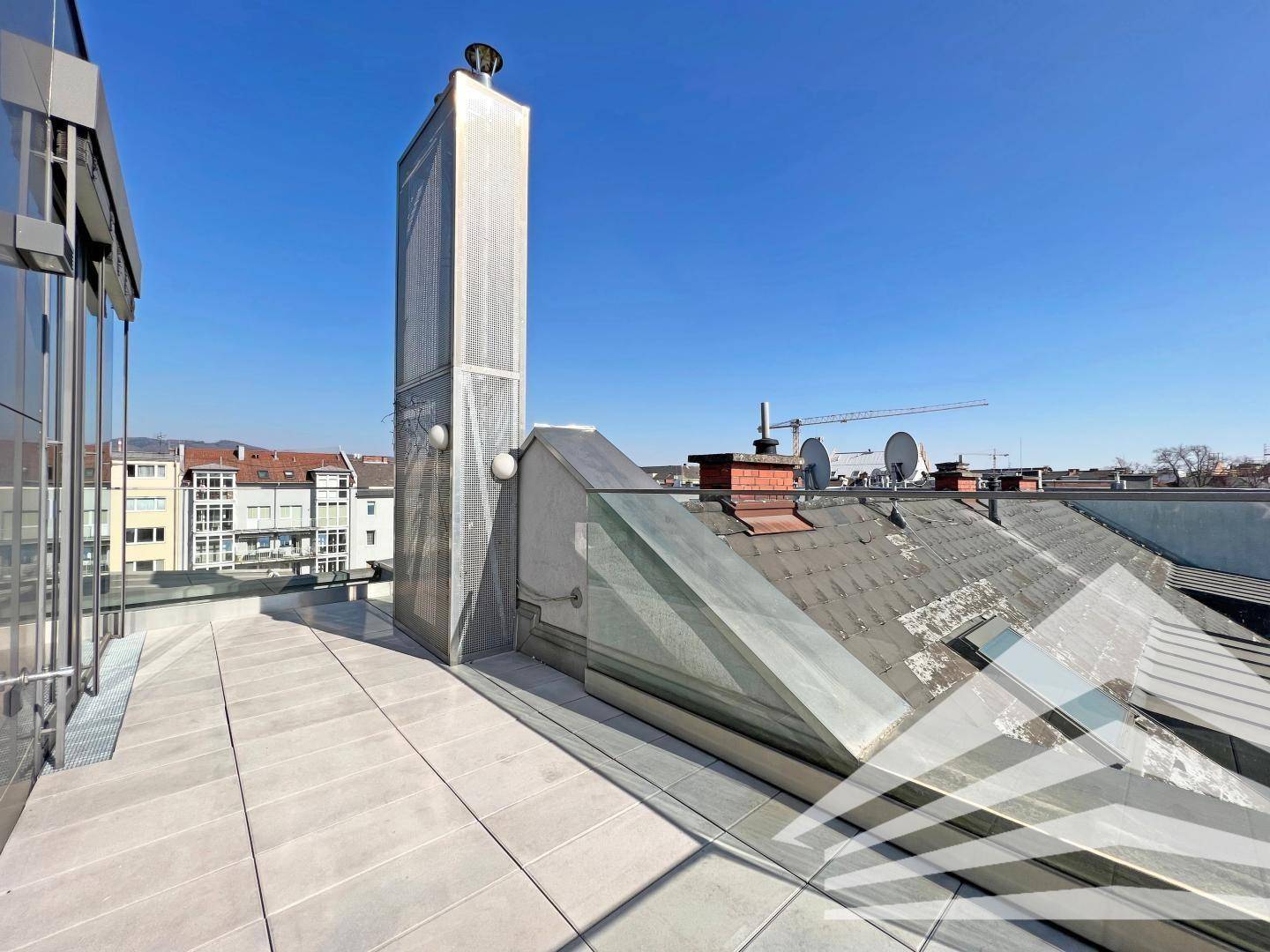 Dachterrasse mit Blick auf die umliegenden Dächer und die Stadt, ideal für Entspannung im Freien.
