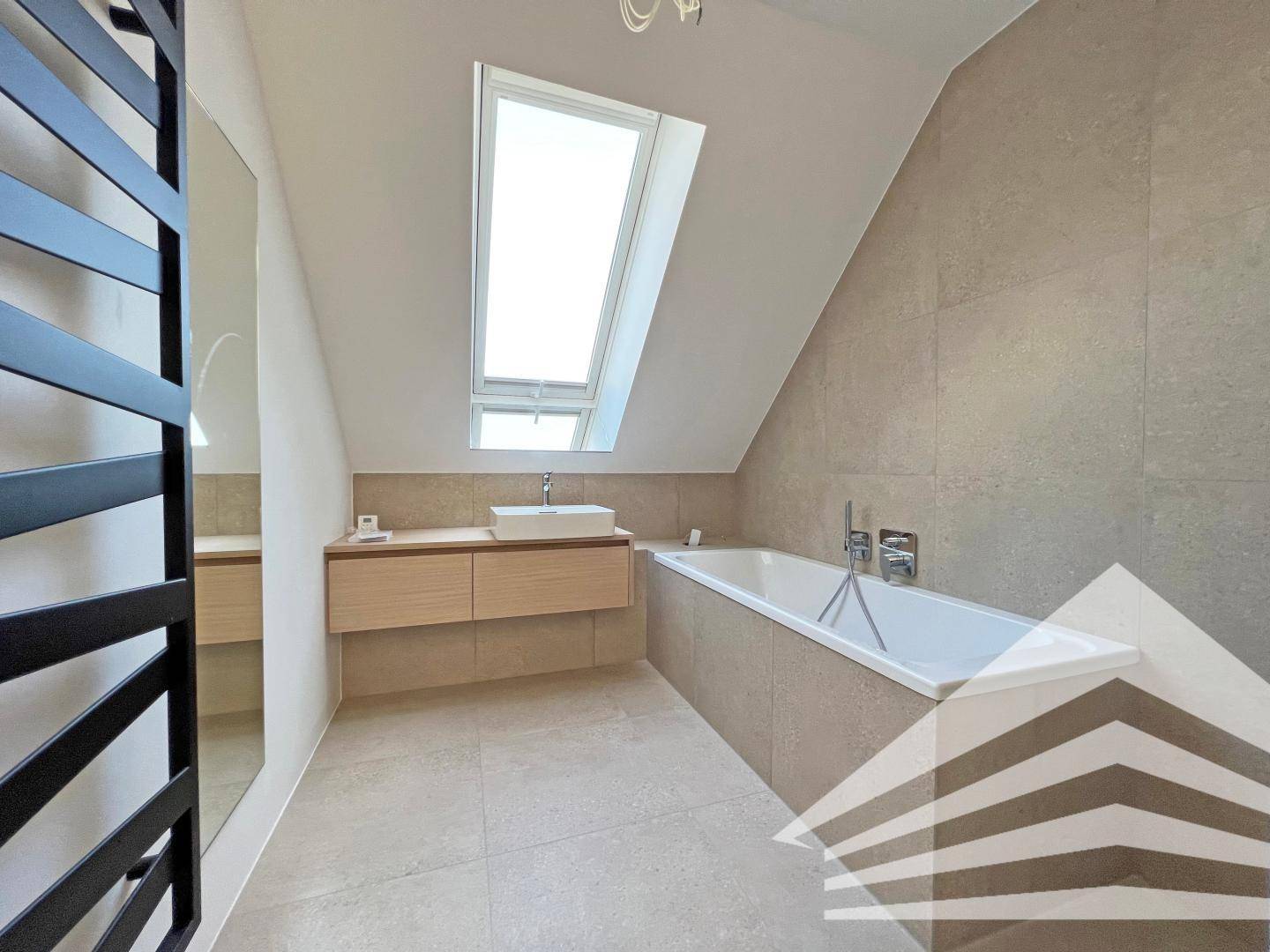 Modernes Badezimmer im Dachgeschoss mit Badewanne, Einzelwaschbecken und Dachfenster.