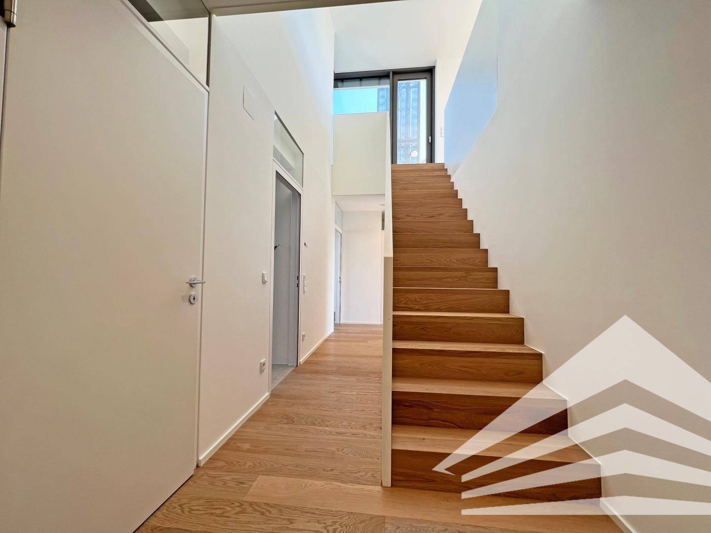 Heller Flur mit Holztreppe und Holzboden, verbindet die verschiedenen Ebenen der Wohnung.
