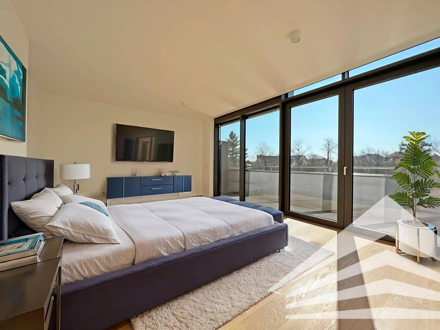 Modern eingerichtetes Schlafzimmer mit Holzboden, großen Fenstern und Zugang zur Terrasse.