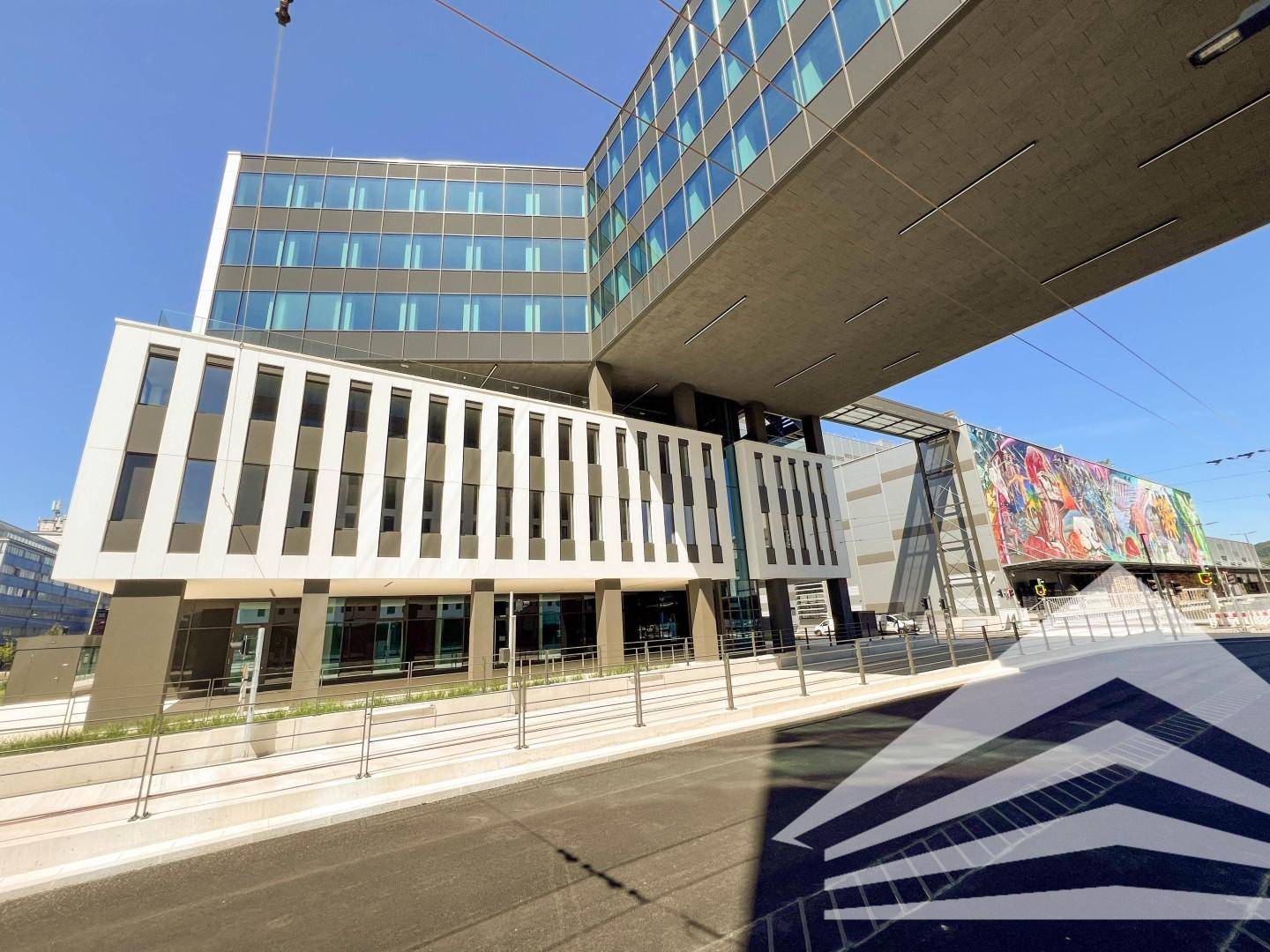 Weitwinkelaufnahme eines modernen Bürokomplexes mit Glasfassaden und einer schwebenden Verbindung zwischen den Gebäudeteilen.