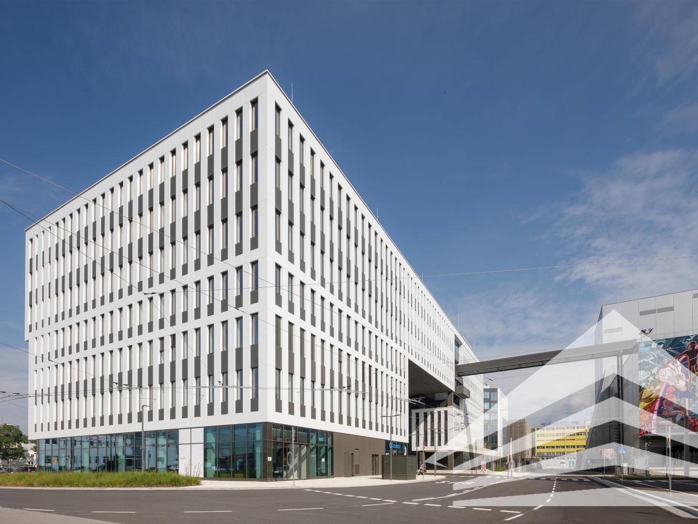 Weitläufige Ansicht eines modernen Bürokomplexes mit markanter weißer Fassade und klarem Himmel, der eine zeitgenössische Architektur zeigt.