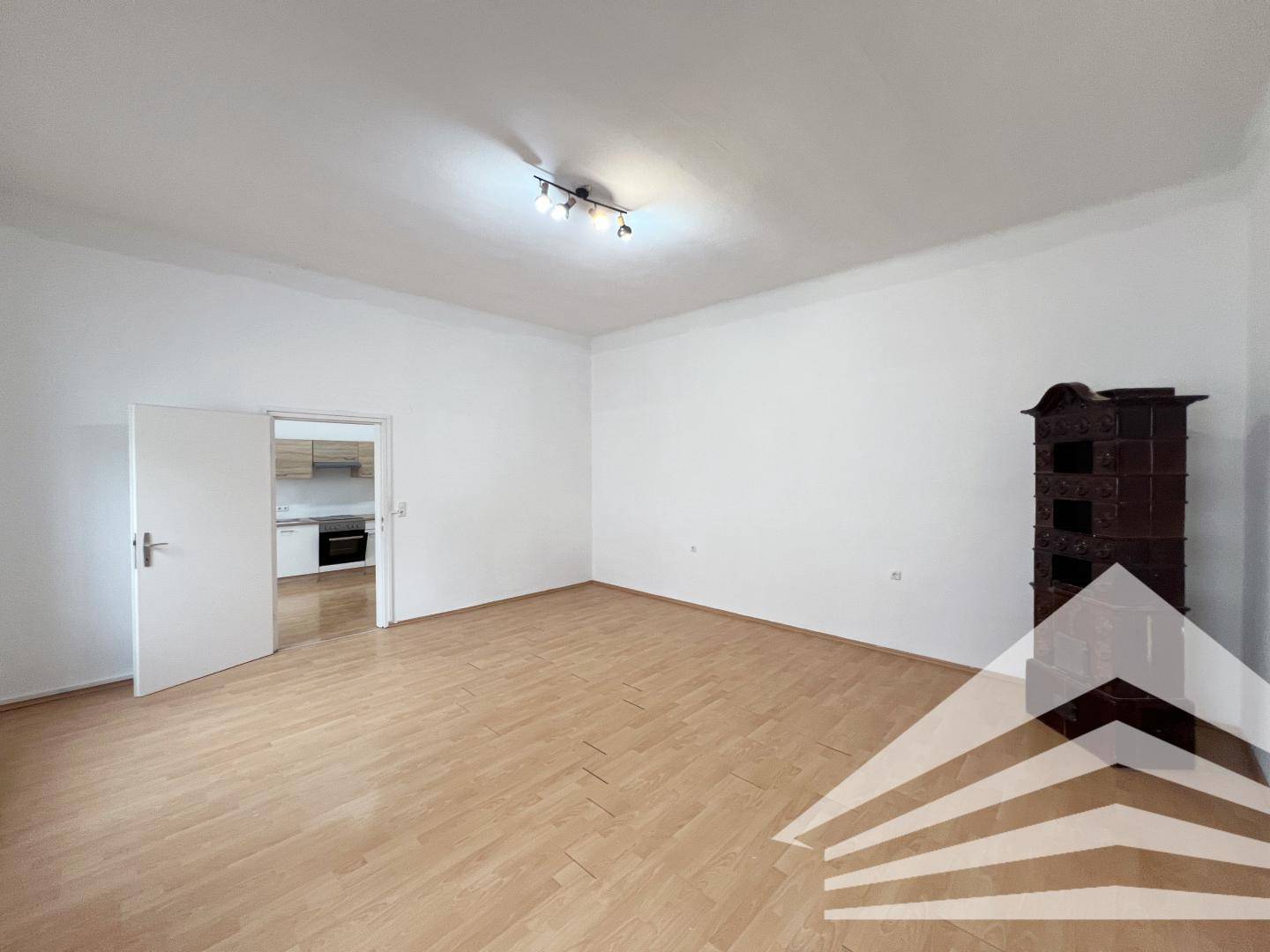 Helles Wohnzimmer mit Parkettboden und einem traditionellen Kachelofen, der Wärme spendet.