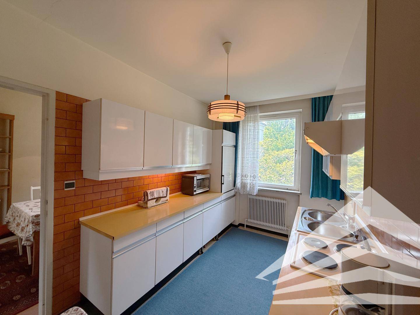 Funktionale Küche mit weißen Schränken, Fliesenrückwand und Fenster.