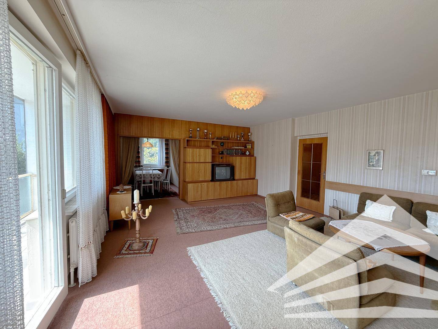 Gemütliches Wohnzimmer im Vintage-Stil mit Teppichboden und Holzvertäfelung.