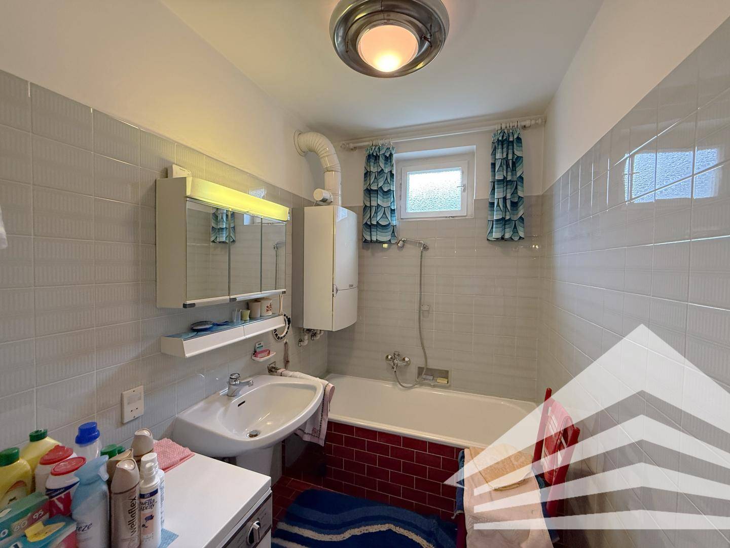 Badezimmer mit Badewanne, Waschbecken und Spiegelschrank.