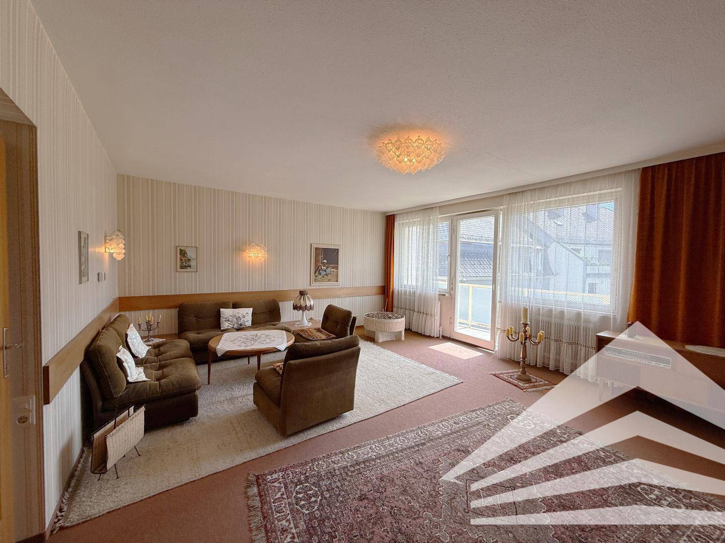 Geräumiges Wohnzimmer mit Zugang zum Balkon, Teppichboden und traditioneller Einrichtung.