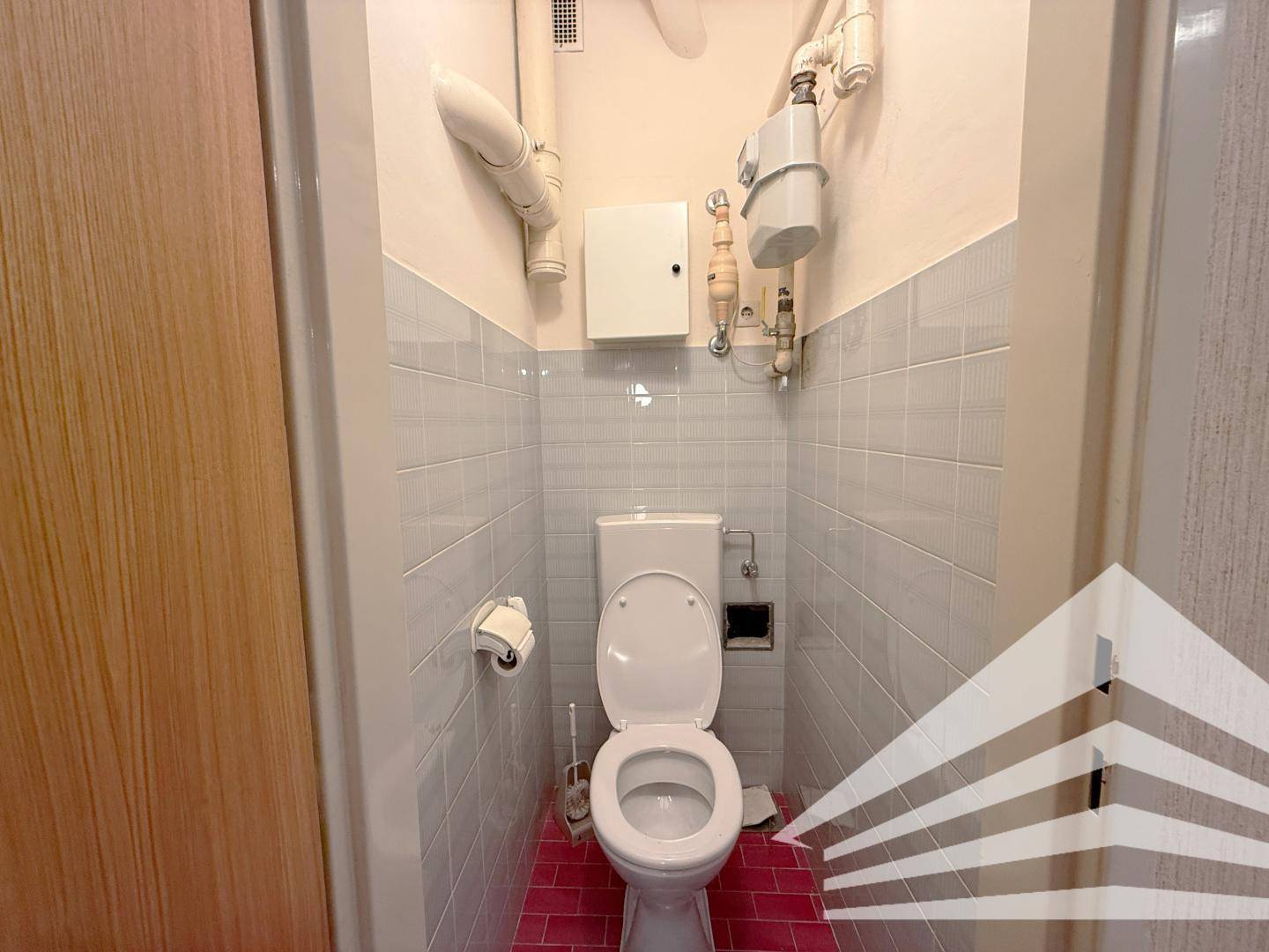 Separate Toilette mit WC und hellen Fliesen an den Wänden.