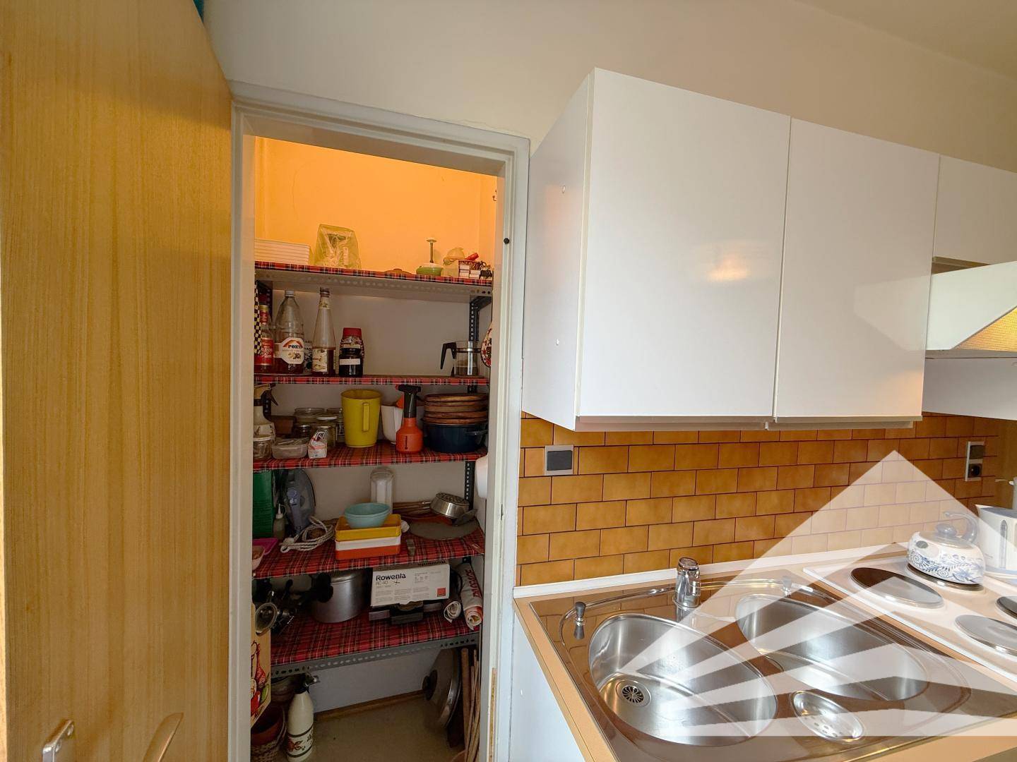 Gut organisierte Speisekammer mit Regalen für Vorräte und Küchenutensilien.