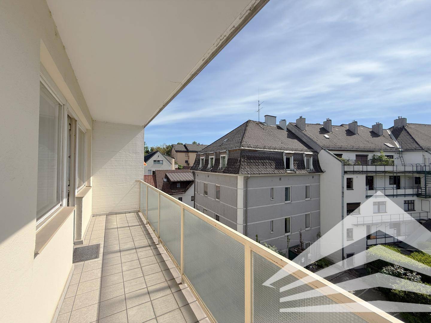 Heller Balkon mit Fliesenboden und weitem Blick über die Dächer der Stadt.