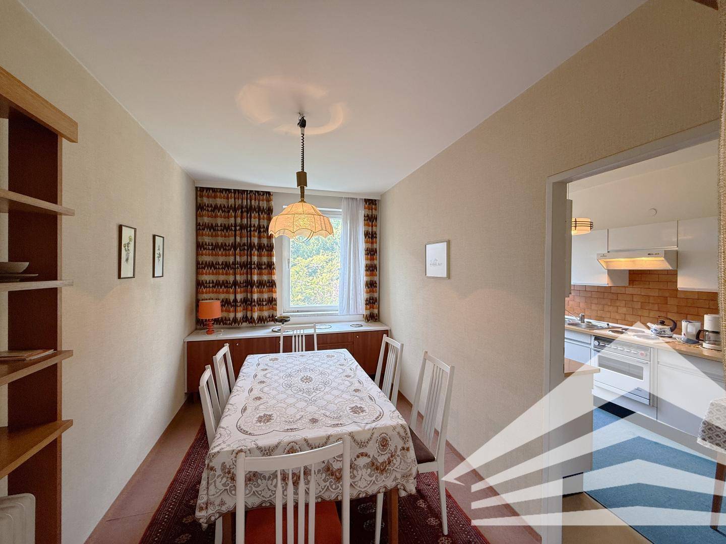 Separates Esszimmer mit großem Tisch, Teppichboden und Zugang zur Küche.