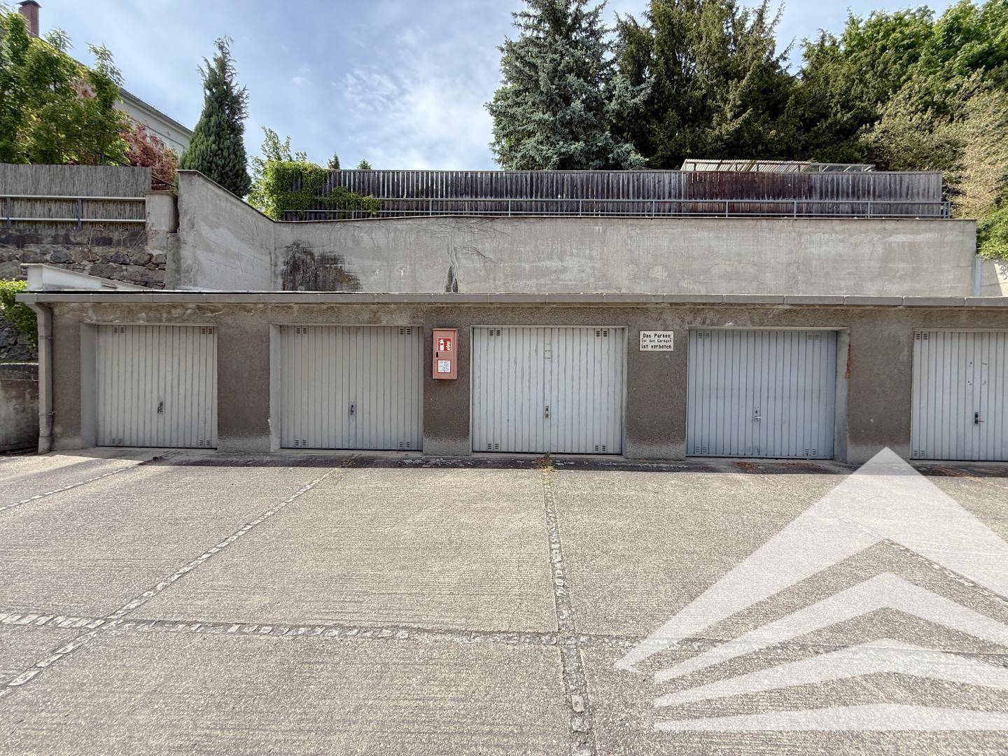 Reihe von Garagenboxen mit Betonvorplatz und Zufahrt.