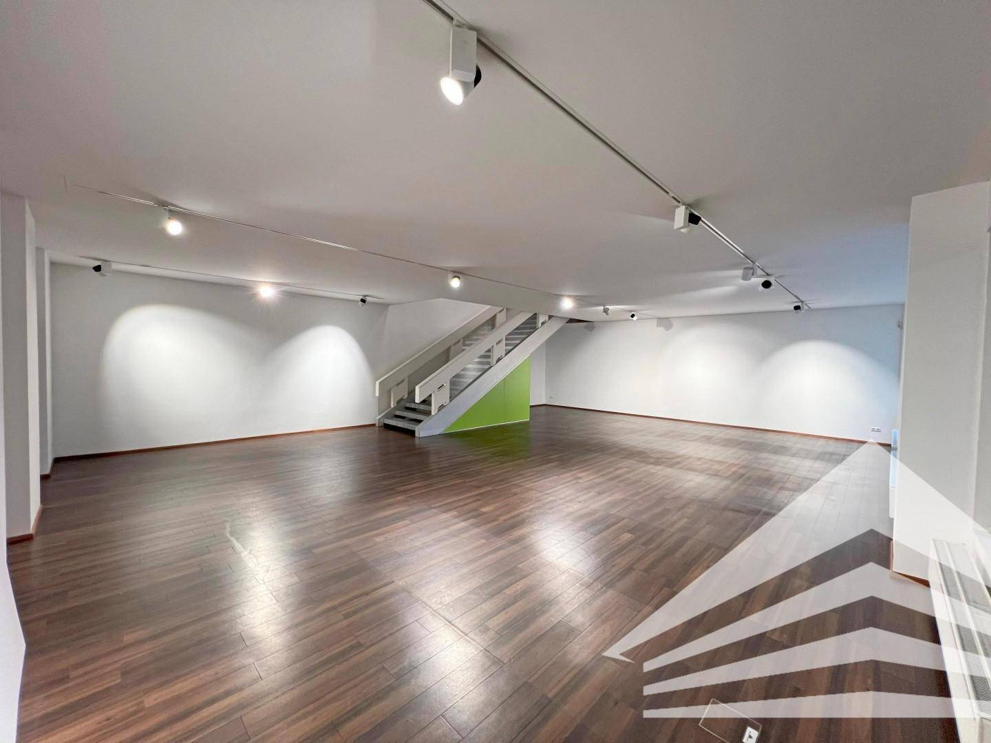 Heller Gewerberaum mit eleganter Treppe und dunklem Holzboden, bereit für individuelle Gestaltung.