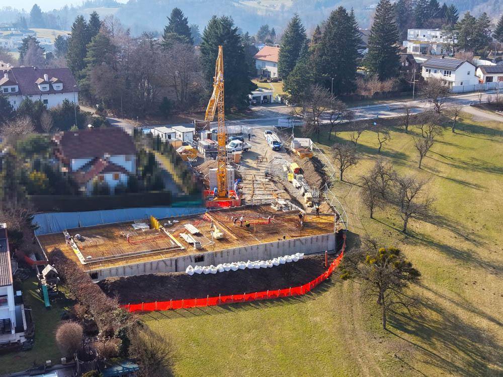 Übersicht der Baustelle mit dem im Bau befindlichen Fundament und einem großen Kran in ländlicher Umgebung.