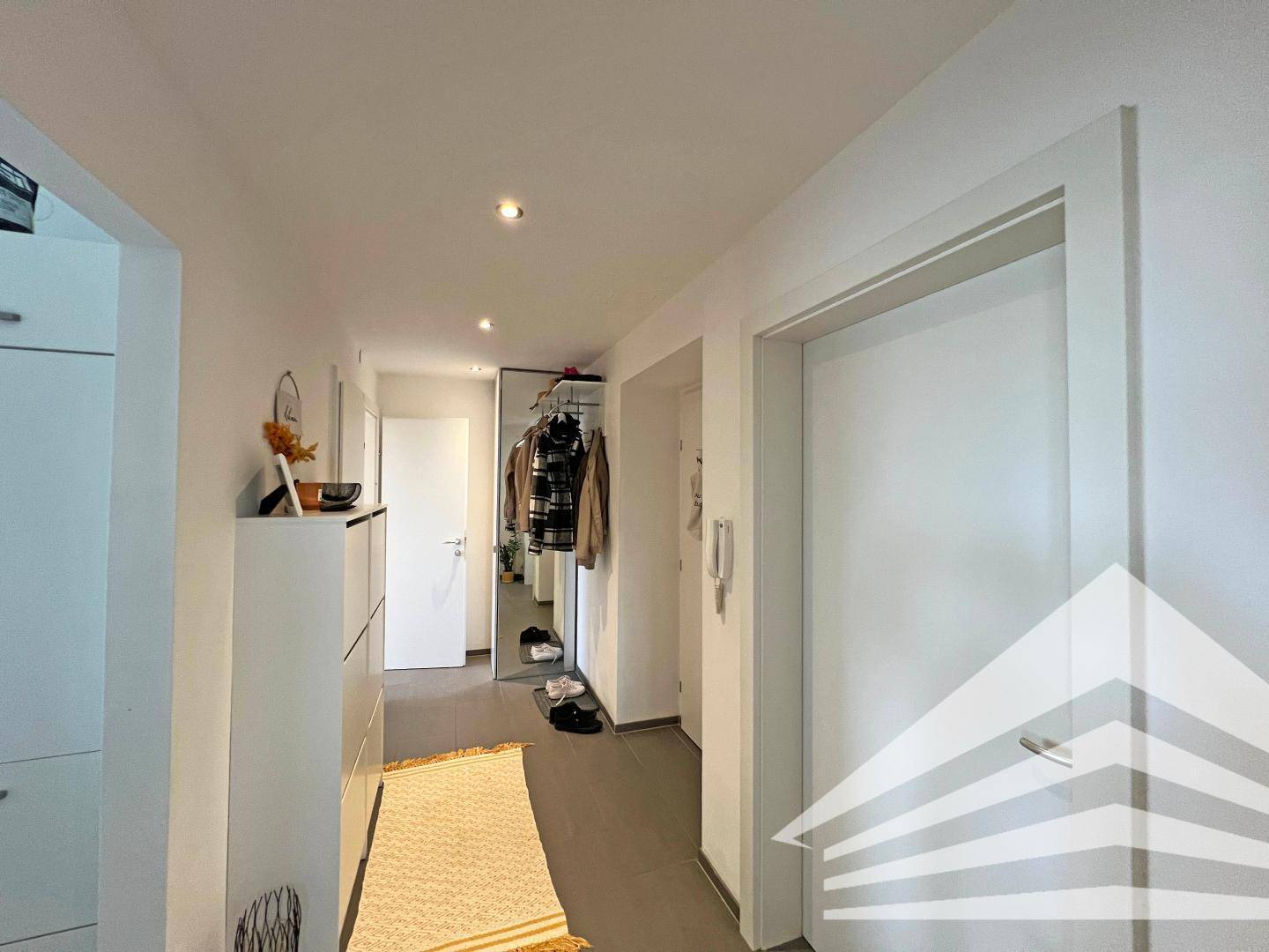 Heller Flur mit Garderobe, Schuhschrank und Spiegel, bietet ausreichend Stauraum.