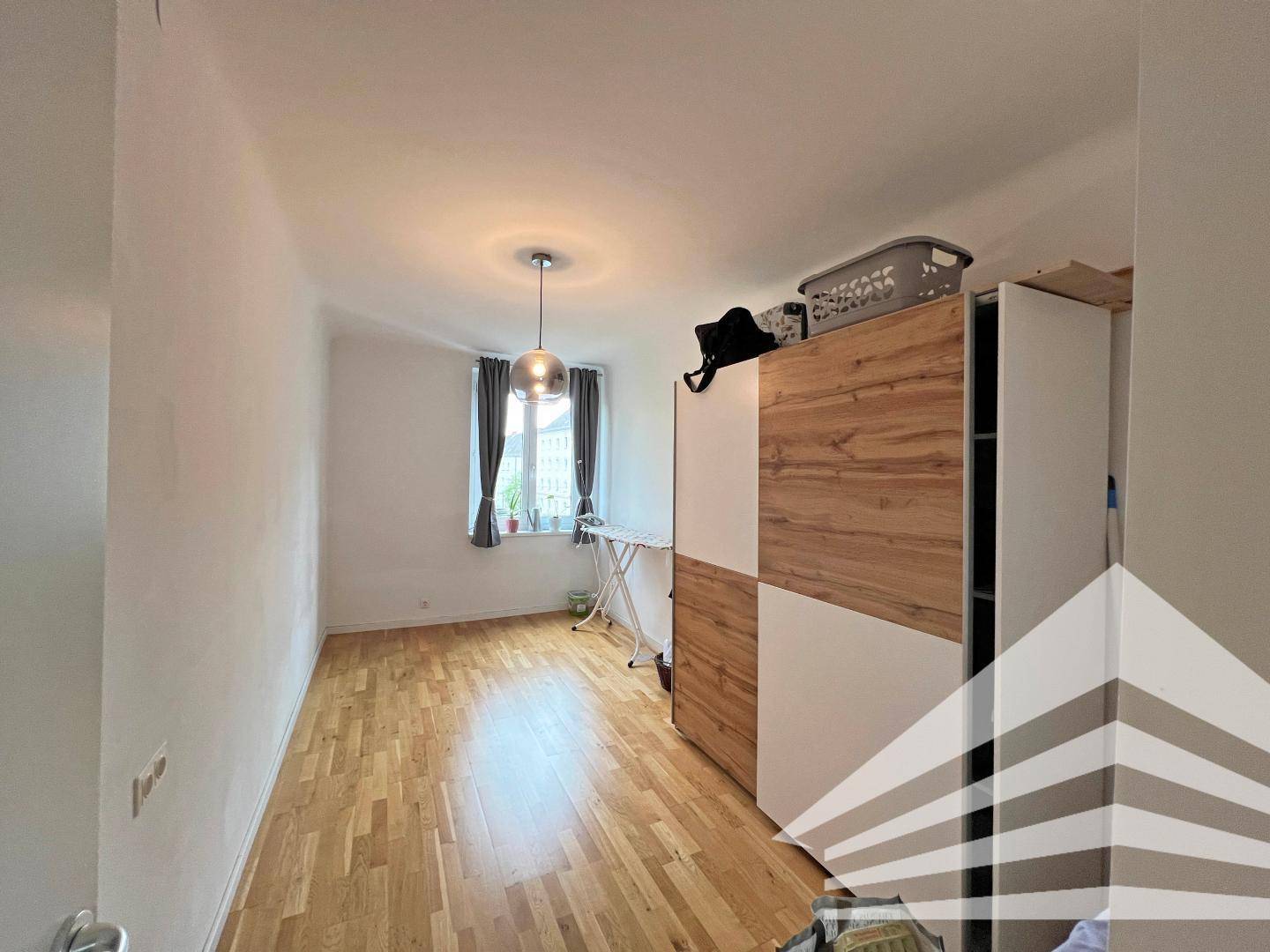 Kleines Zimmer mit Parkettboden und Fenster, ausgestattet mit einem modernen Kleiderschrank.