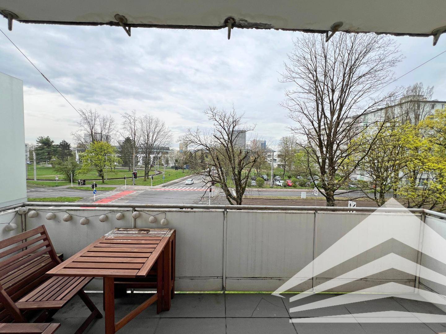 Gemütlicher Balkon mit Holztisch und Bänken, bietet einen Blick auf die Umgebung und Bäume.