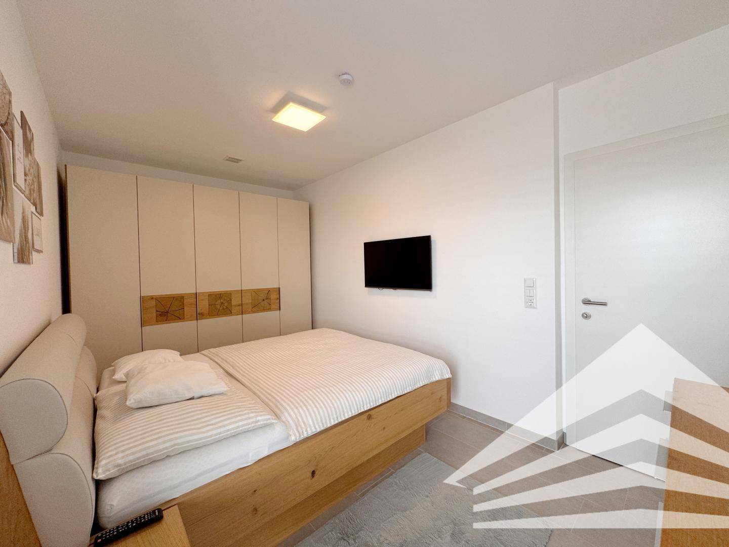 Gemütliches Schlafzimmer mit Holzbett, weißem Kleiderschrank und Wanddekoration.