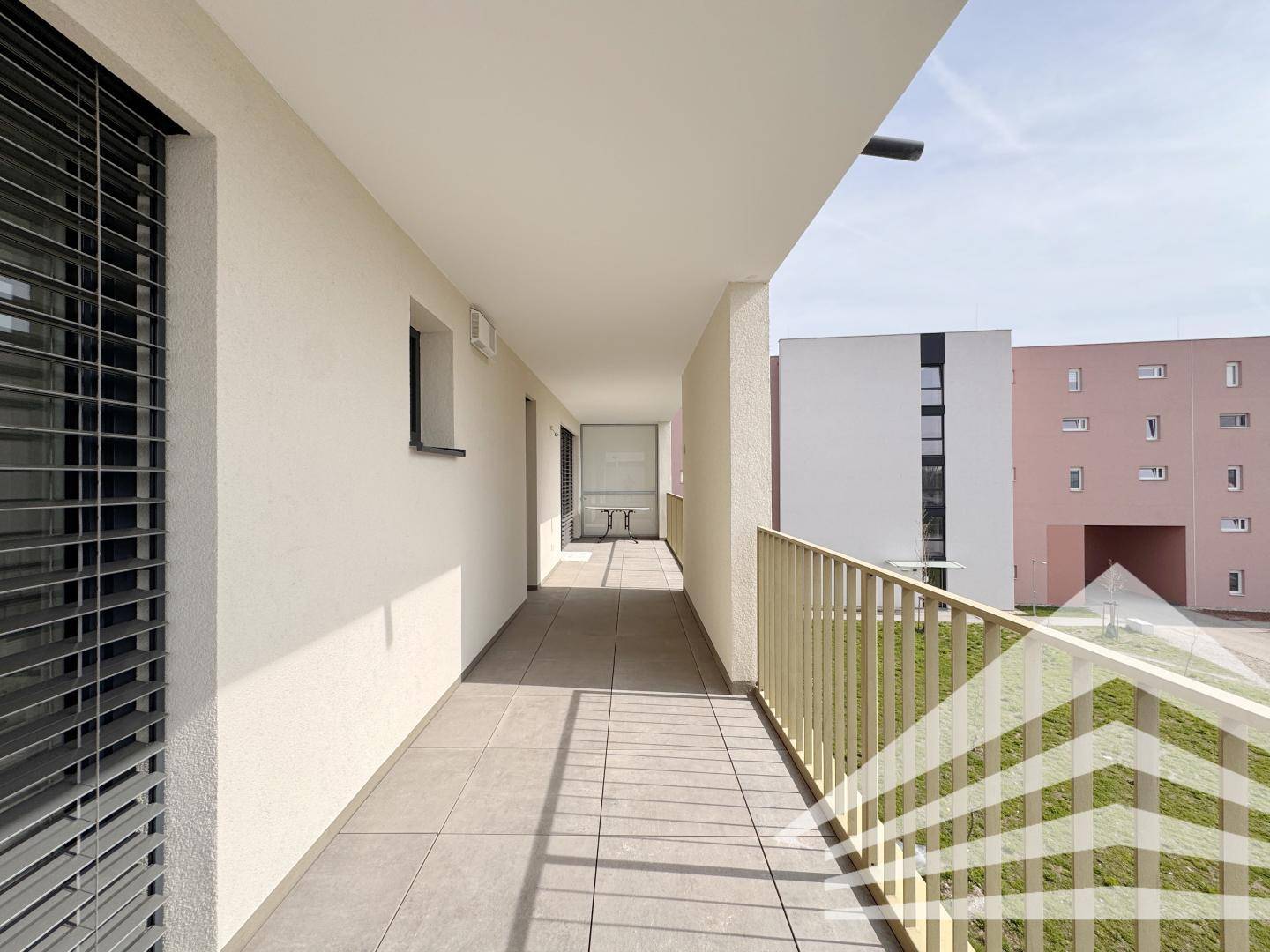 Geräumiger Balkon mit Fliesenboden und Jalousien an den Fenstern der angrenzenden Räume.