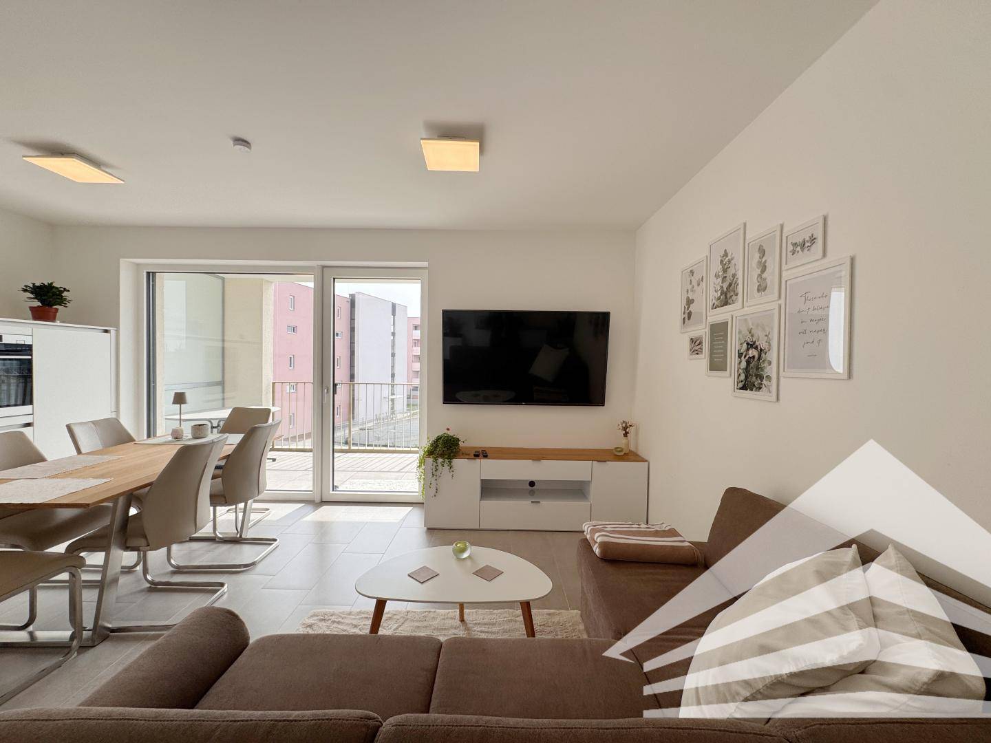 Geräumiger Wohnbereich mit Esstisch, Sofa und Blick auf den Balkon.