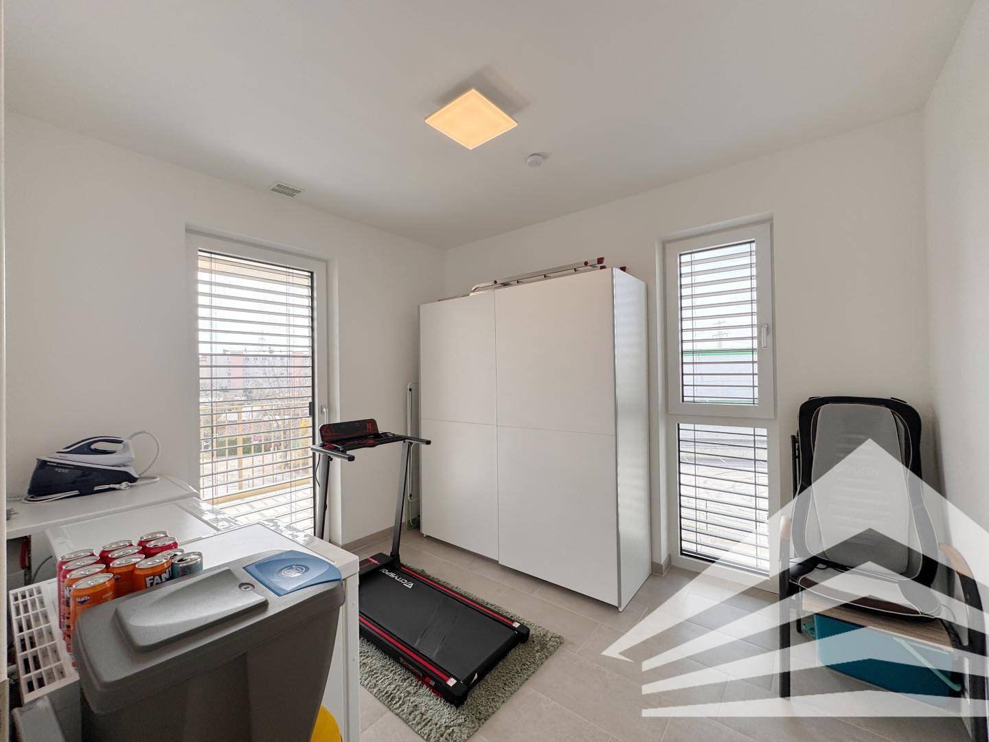 Vielseitiger Raum mit Laufband, Schrank und Zugang zu einem weiteren Balkon.