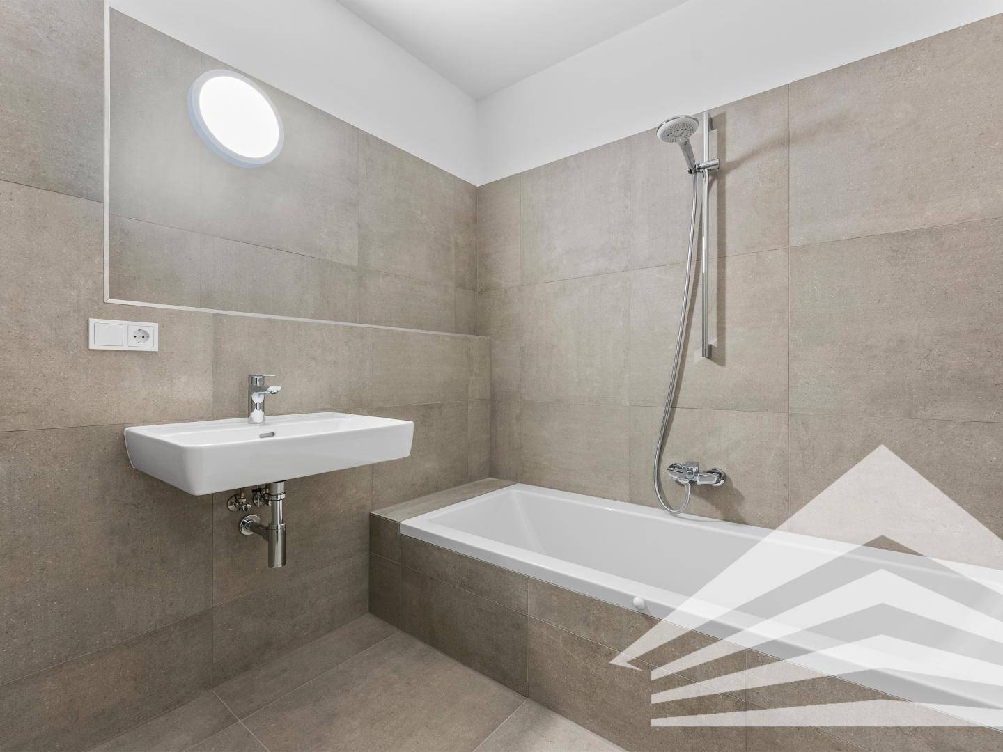 Modernes Badezimmer mit Badewanne, Duscharmatur und grauen Fliesen.
