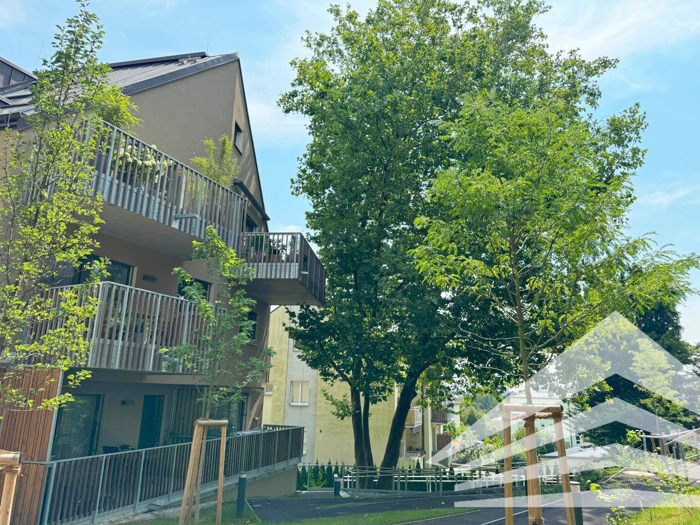 Moderne Wohnanlage mit Balkonen und viel Grün in der Umgebung.