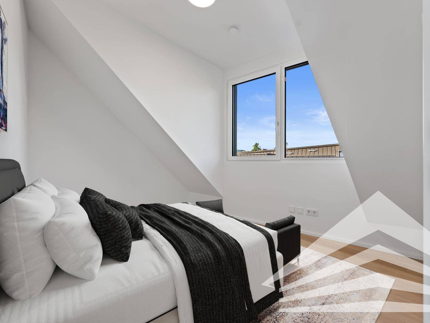 Modern eingerichtetes Schlafzimmer im Dachgeschoss mit Bett und Blick aus dem Fenster.