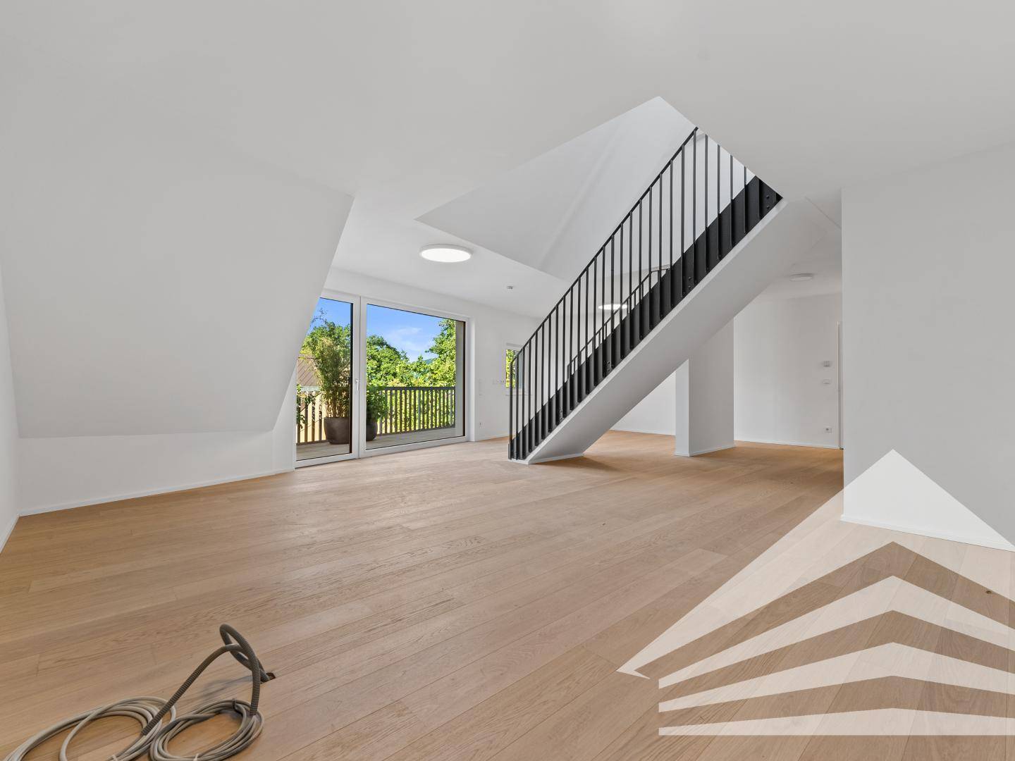 Heller, offener Wohnbereich mit Holzparkettboden, moderner Treppe und Zugang zur Außenterrasse.