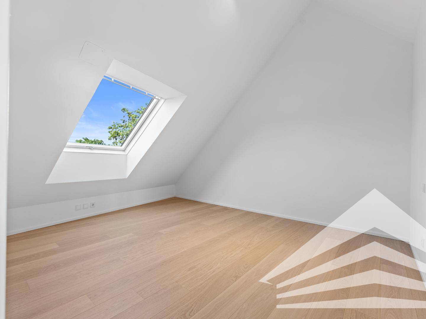 Helles Schlafzimmer im Dachgeschoss mit Holzparkettboden, Dachschrägen und großem Dachfenster.