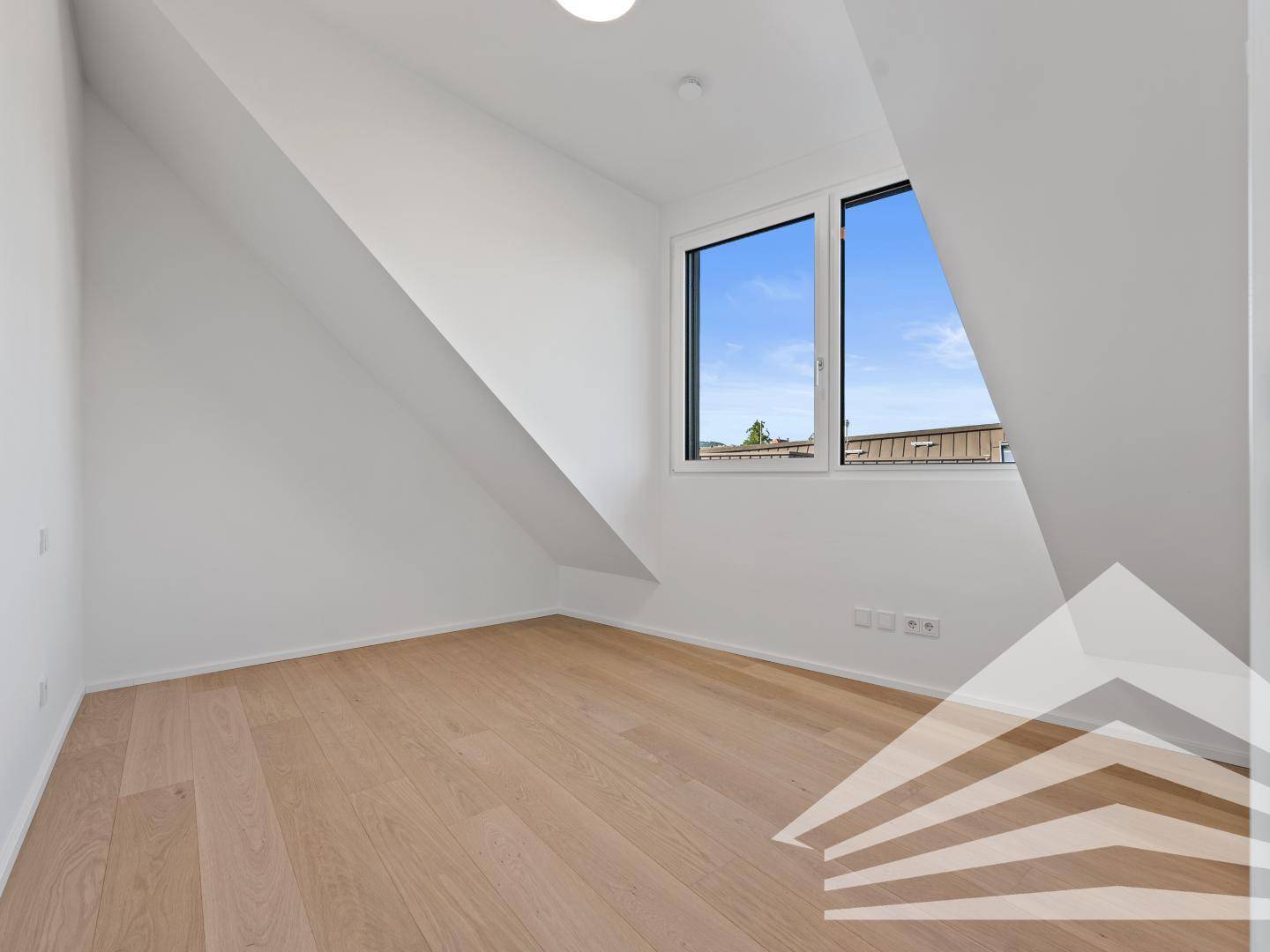 Schlafzimmer im Dachgeschoss mit Holzparkettboden, Dachschrägen und Fenster mit Ausblick.