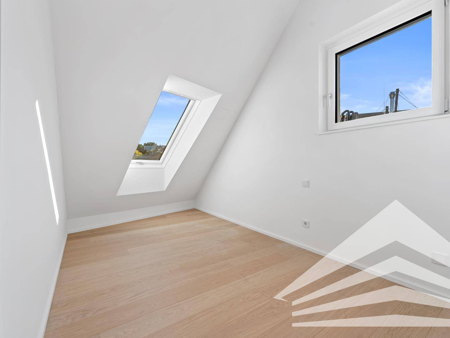 Helles Schlafzimmer im Dachgeschoss mit Holzparkettboden, Dachschrägen und zwei Fenstern für viel Licht.
