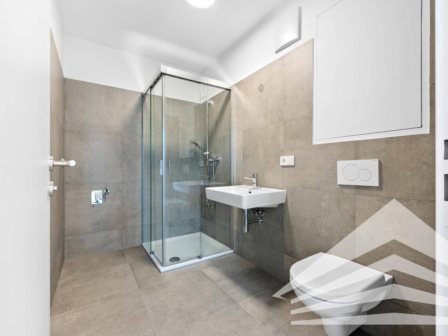 Modernes Badezimmer mit grauen Fliesen, Duschkabine und wandhängendem WC, in neuwertigem Zustand.