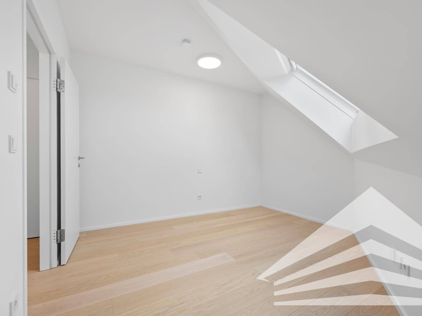 Unmöbliertes Schlafzimmer mit Dachfenster und hellem Holzfußboden, ideal für ein Kinderzimmer.