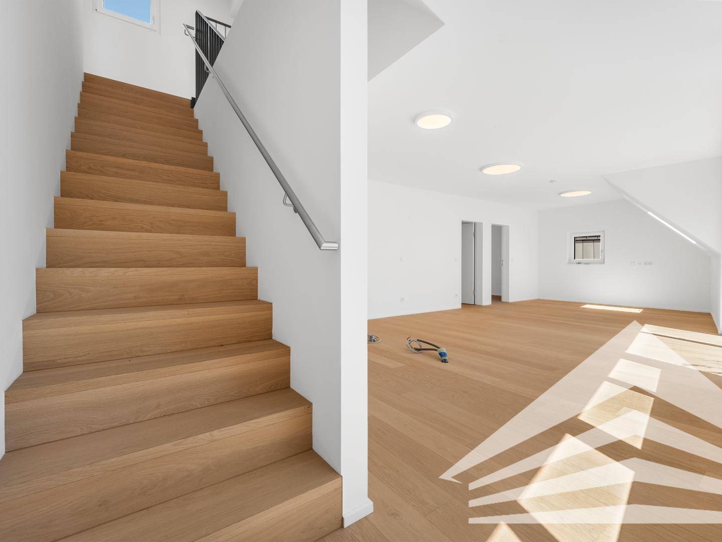 Moderne Holztreppe mit Metallgeländer, die zu einem hellen Wohnbereich führt.