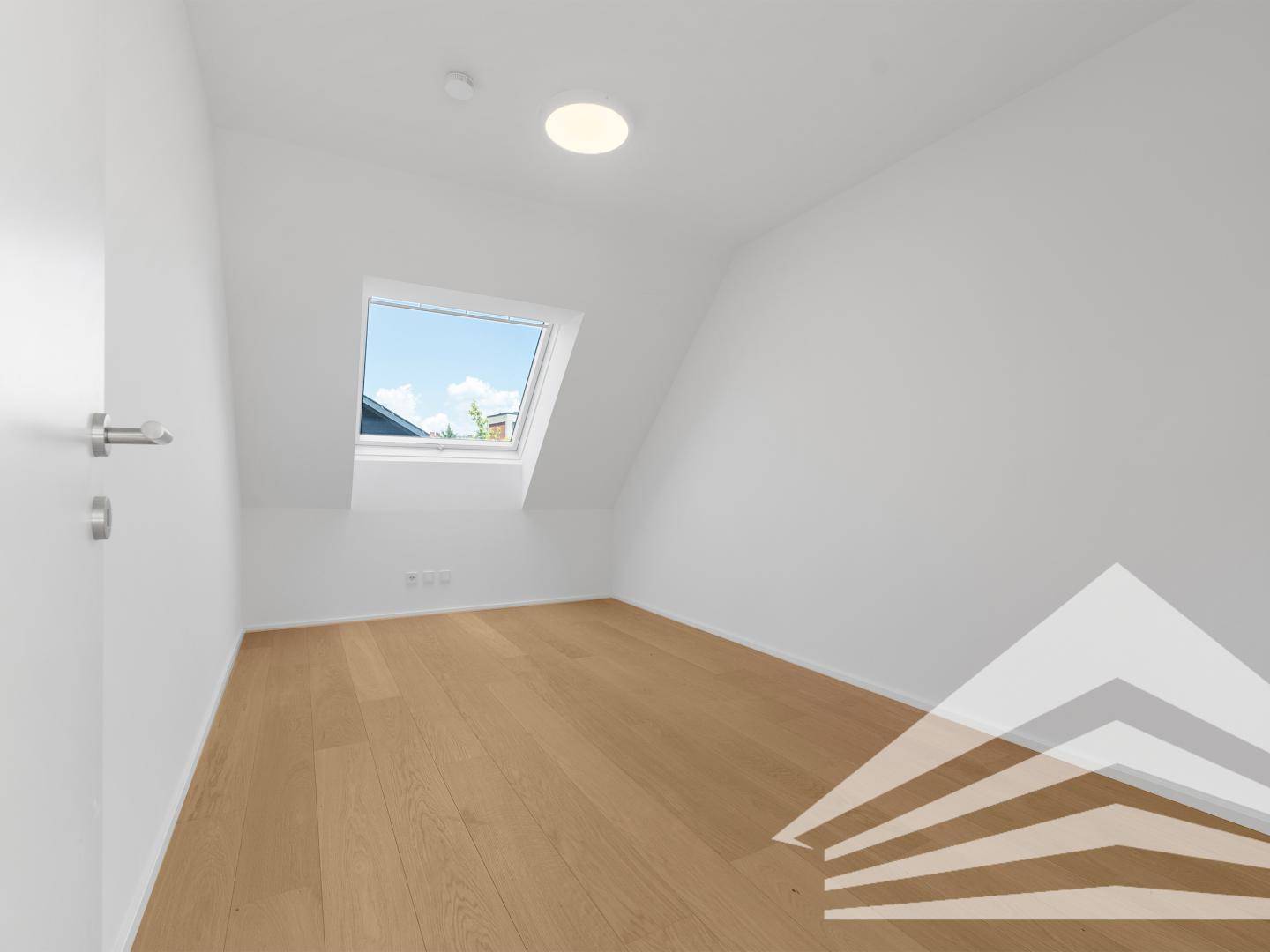 Helles Zimmer im Dachgeschoss mit Holzboden und großem Dachfenster.