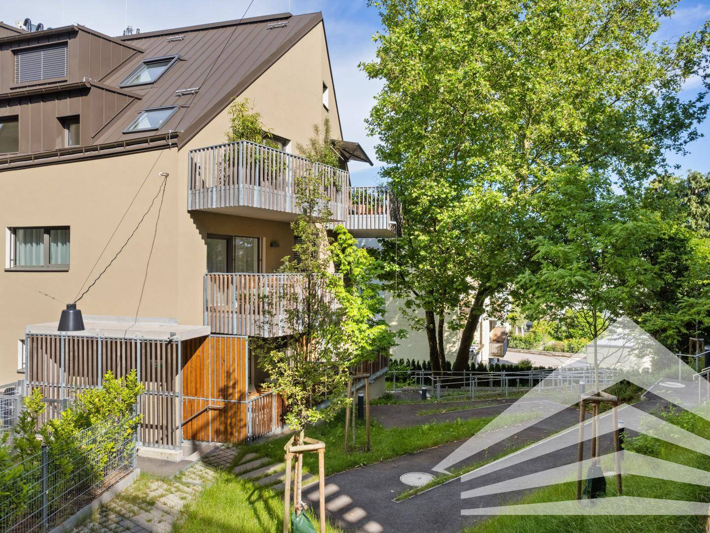 Moderne Wohnanlage mit mehreren Balkonen und viel Grün in der Umgebung.