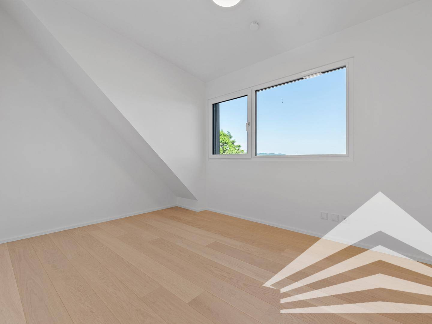 Helles Zimmer mit Holzboden und weitem Ausblick durch das große Fenster.