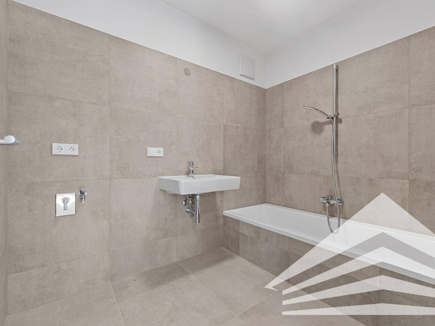 Modernes Badezimmer mit hellgrauen Fliesen, Waschbecken und einer Badewanne.