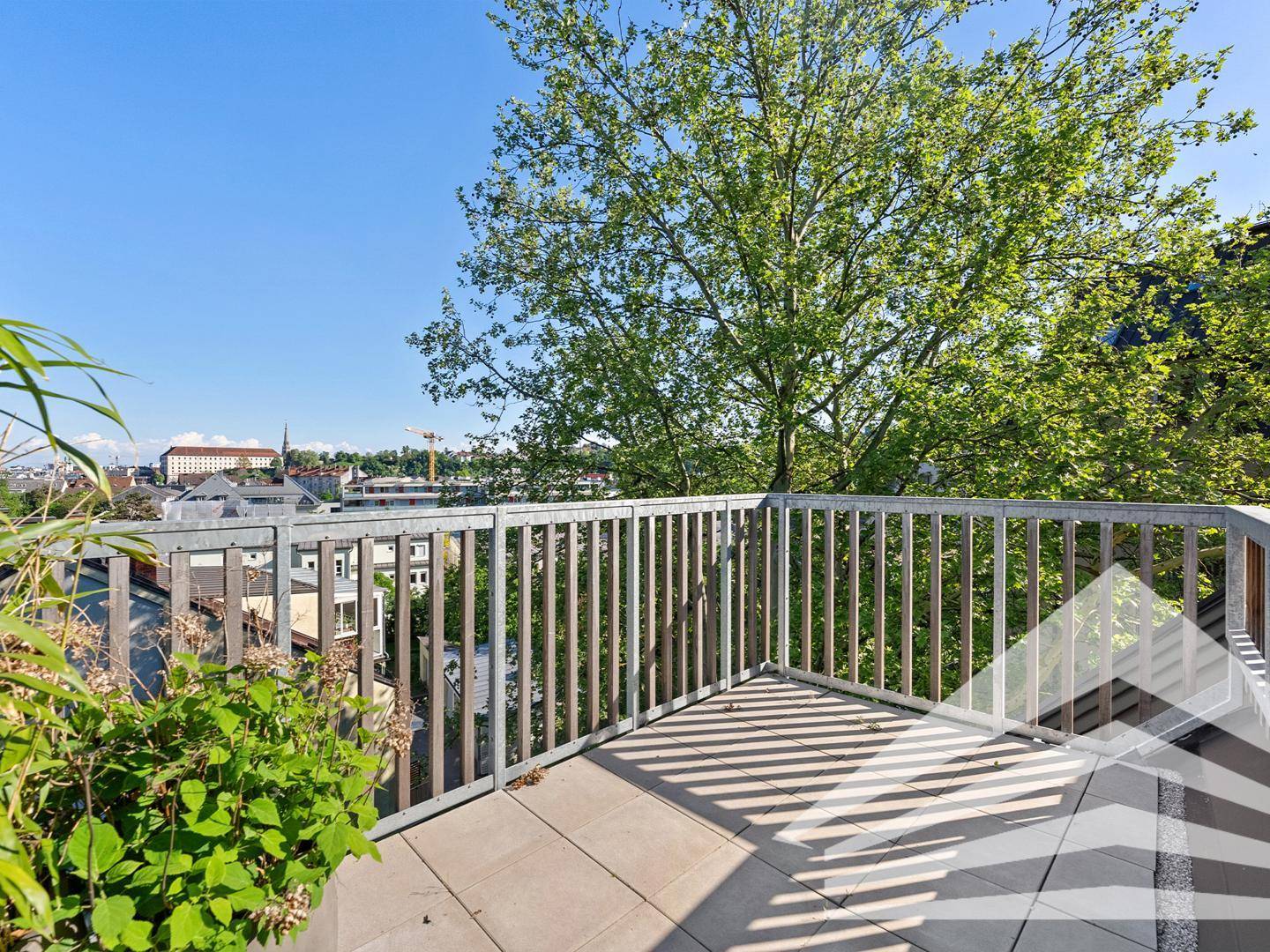Sonniger Balkon mit weitem Blick über die Stadt und viel Grün in der Umgebung.