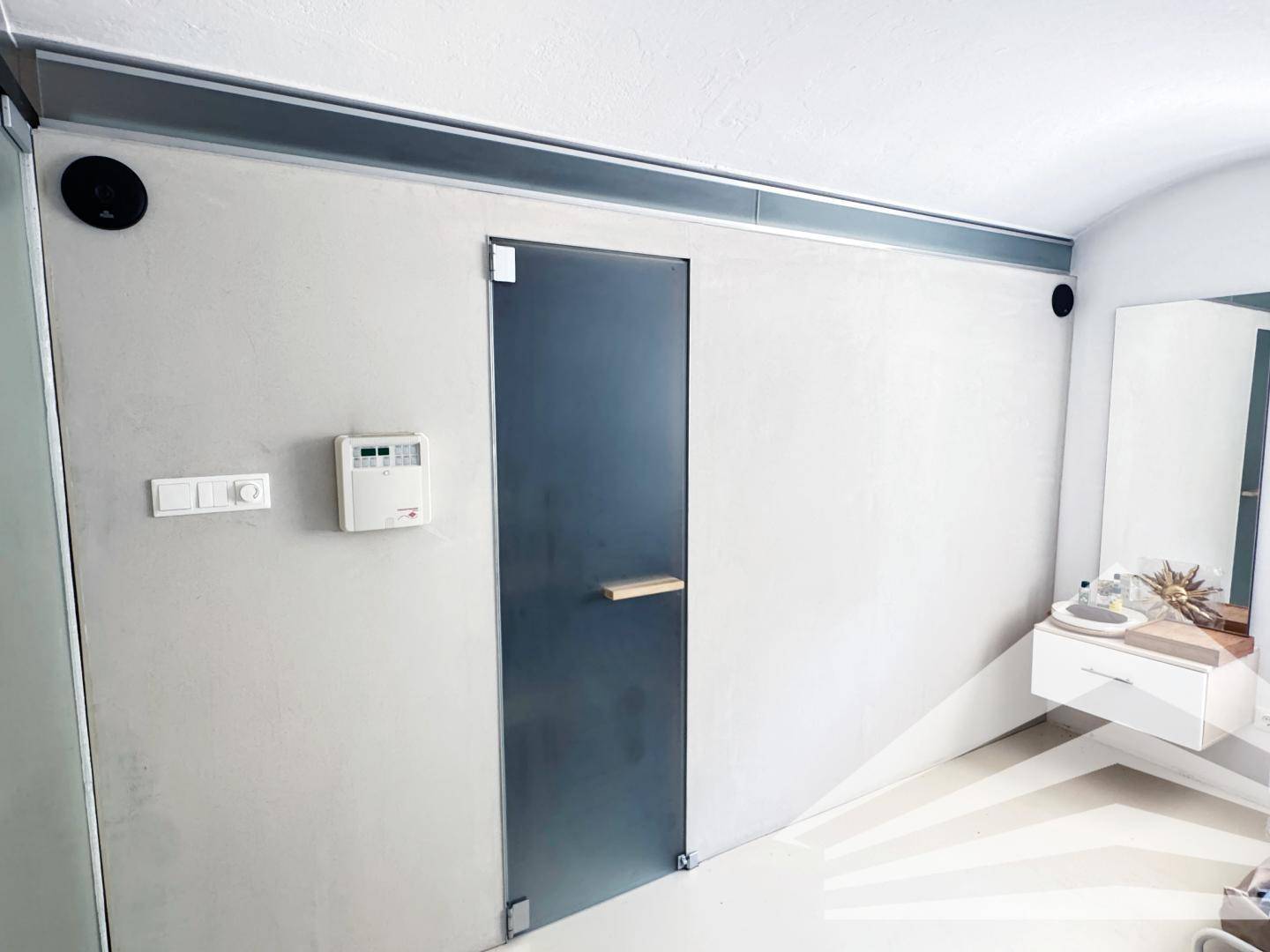 Moderner Wellnessbereich mit Sauna, Waschbecken und minimalistischem Design.
