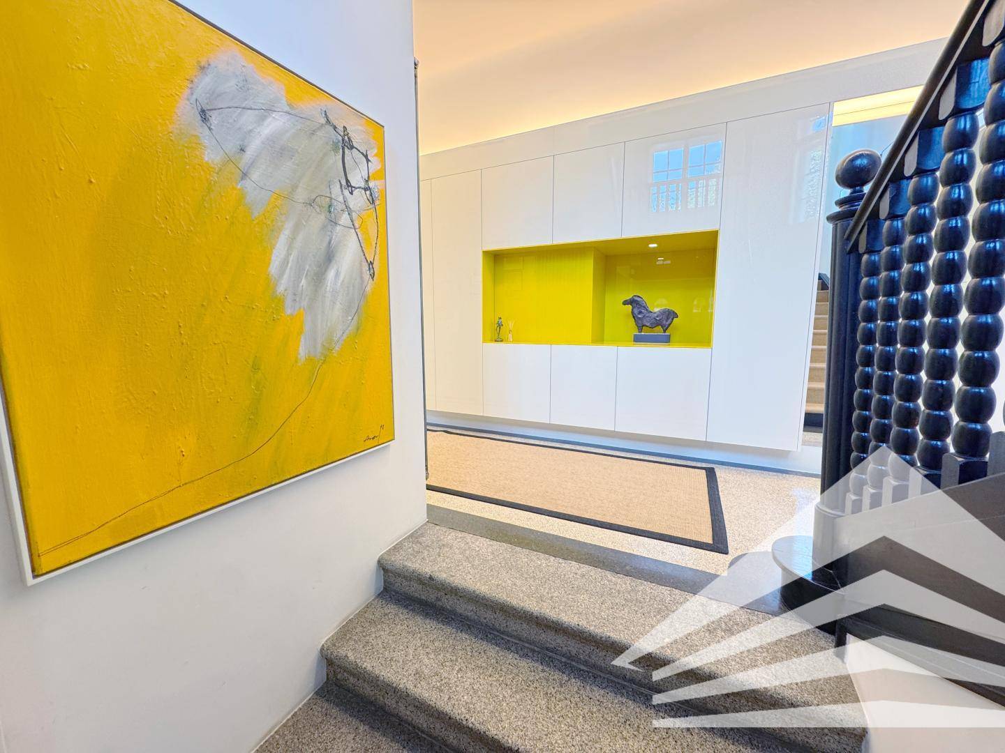 Heller Flur mit moderner Kunst, Einbauschränken und Treppenaufgang.