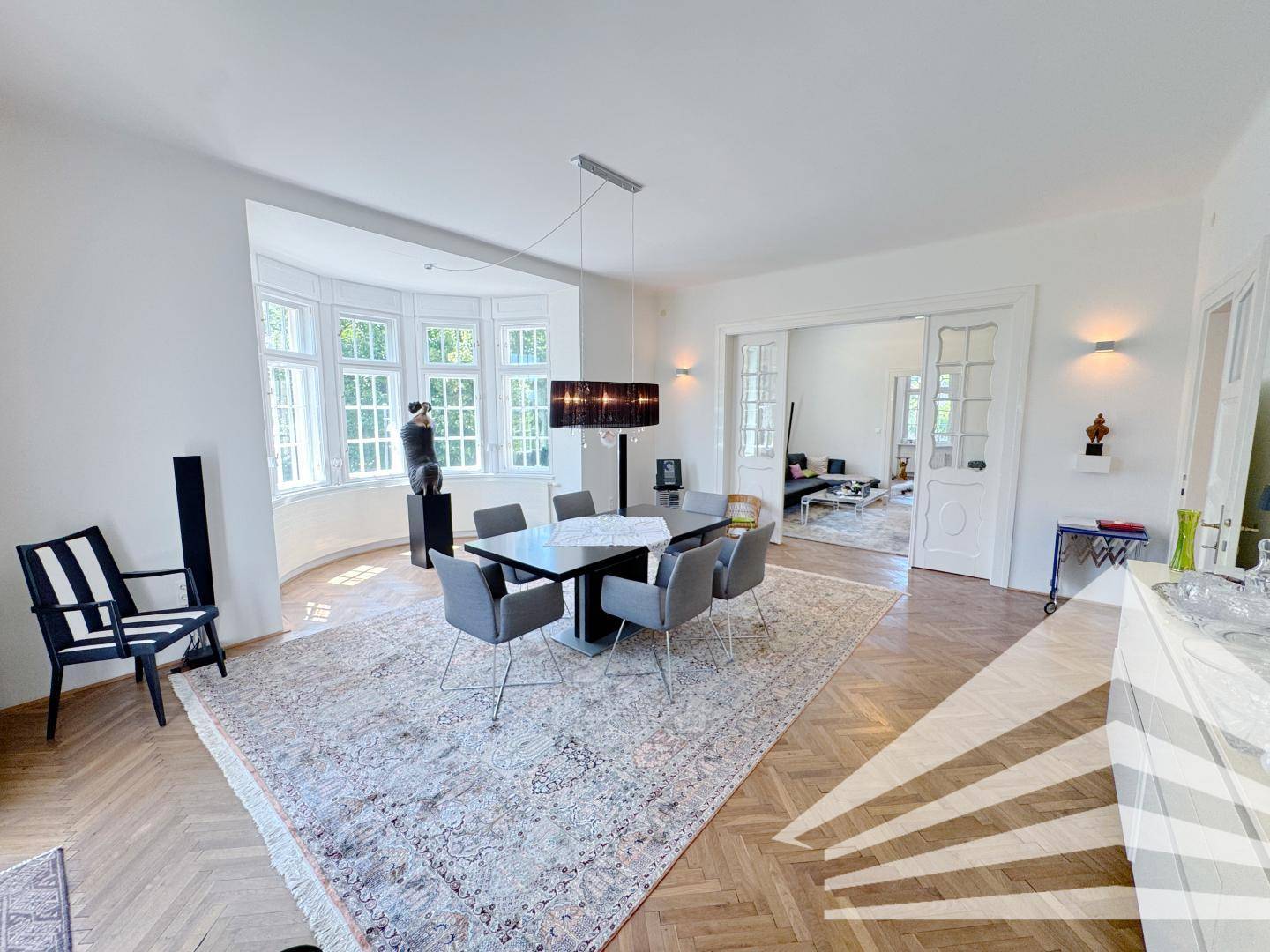Elegantes Esszimmer mit Parkettboden, großem Esstisch und Zugang zum Wohnbereich.