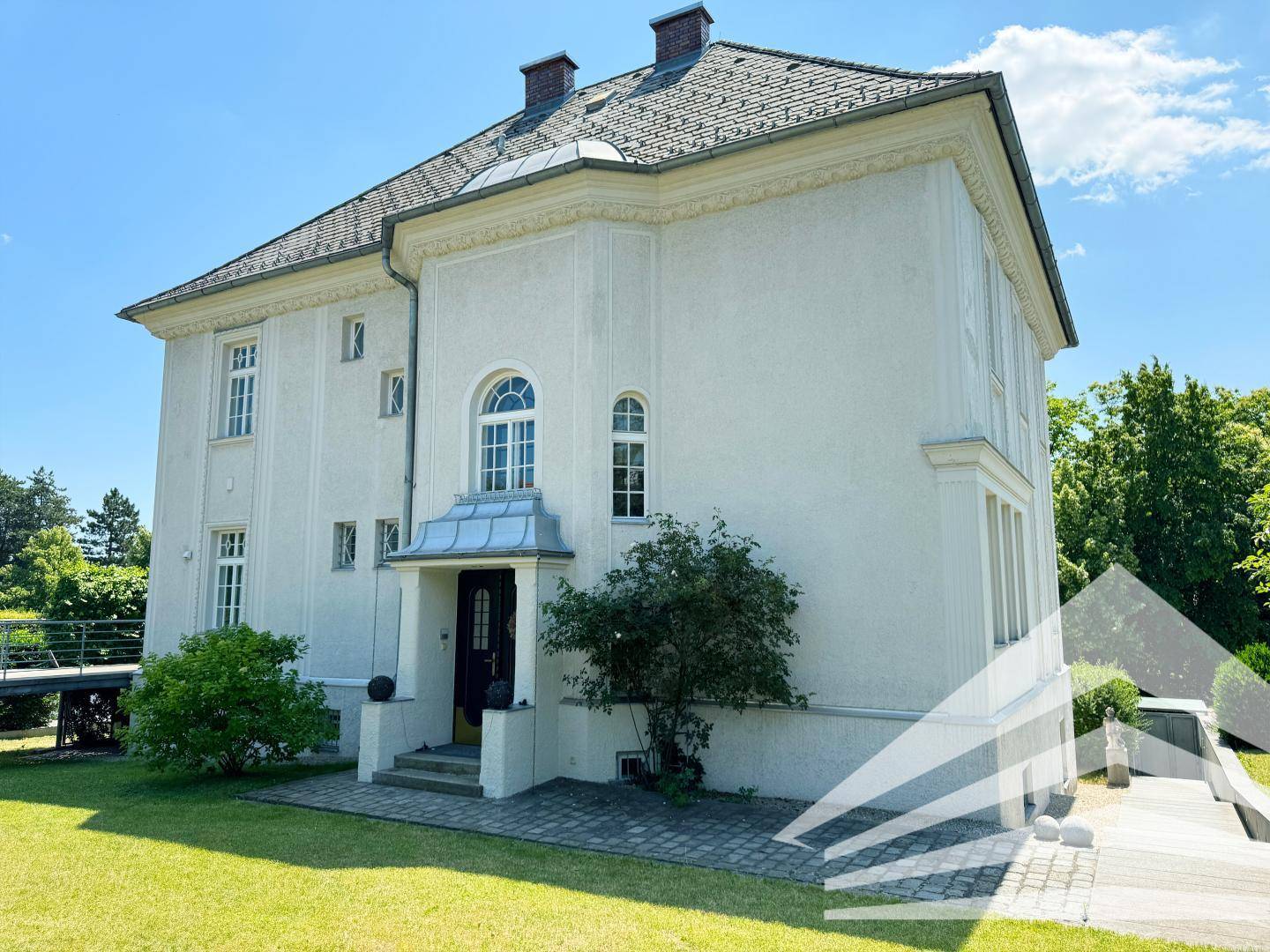 Repräsentative Villa mit klassischer Architektur, weißer Fassade und gepflegtem Vorgarten.
