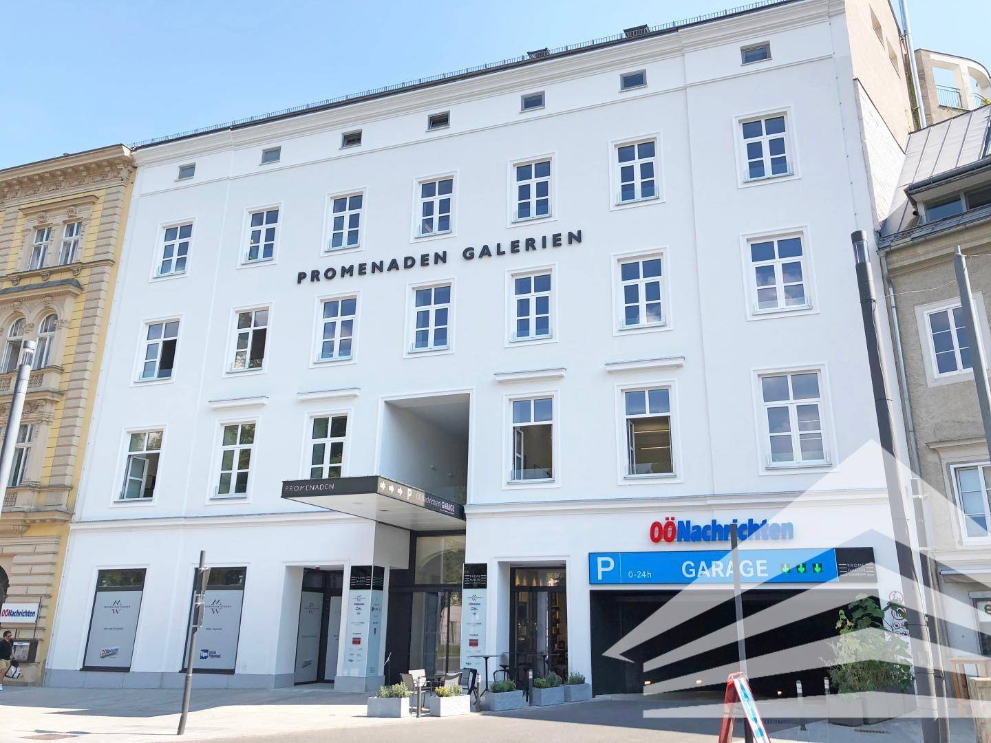 Weiße, moderne Gebäudefassade mit vielen Fenstern und einem Eingangsbereich zu den "Promenaden Galerien".