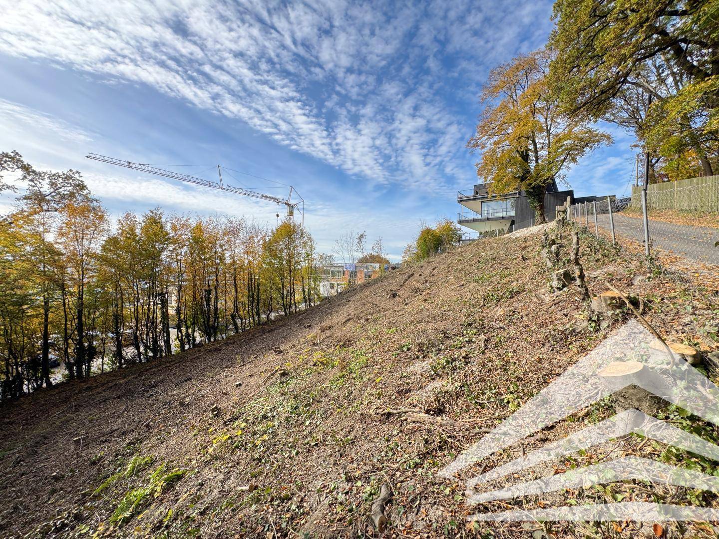 Hanglage mit gerodetem Grundstück und Blick auf die Baustelle in der Ferne.