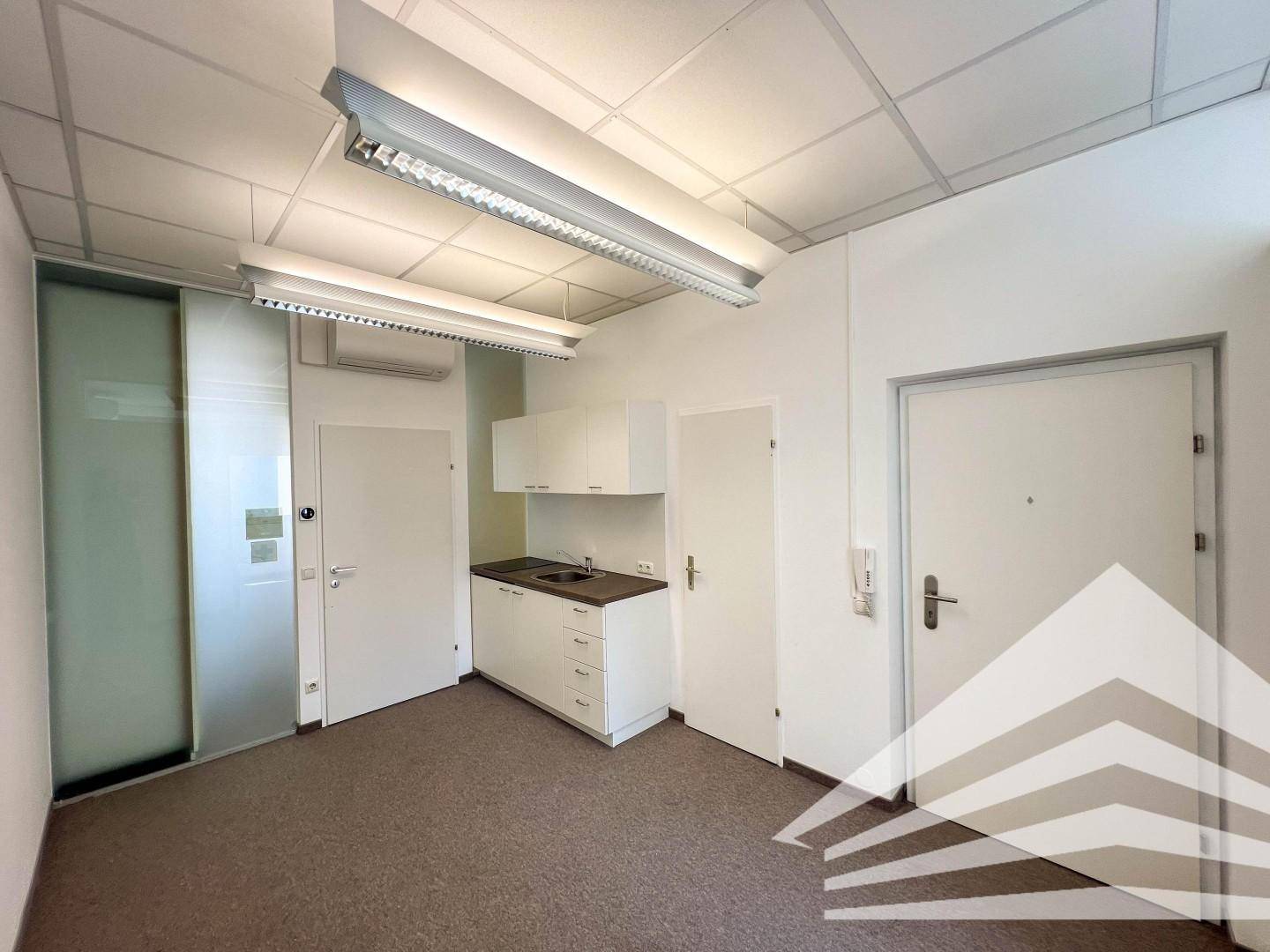 Büroraum mit integrierter Teeküche, Teppichboden und abgehängter Decke, ideal für Pausen.