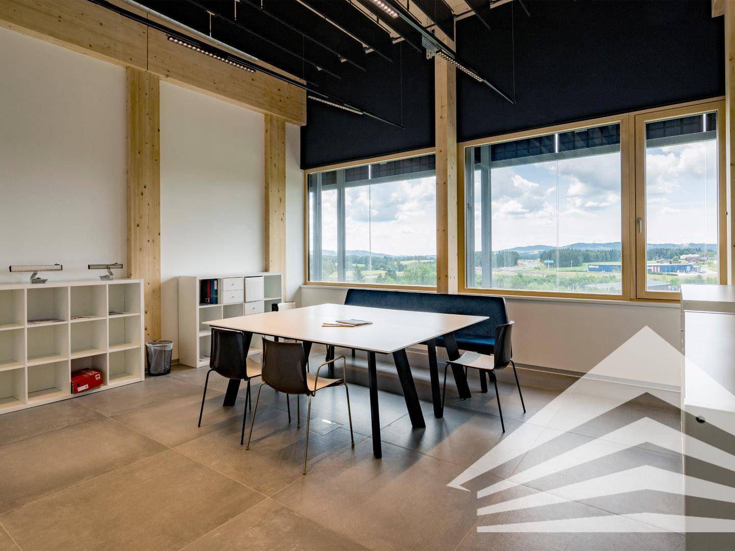 Besprechungs- oder Pausenbereich im Büro mit Tisch, Stühlen und großen Fenstern mit Weitblick.